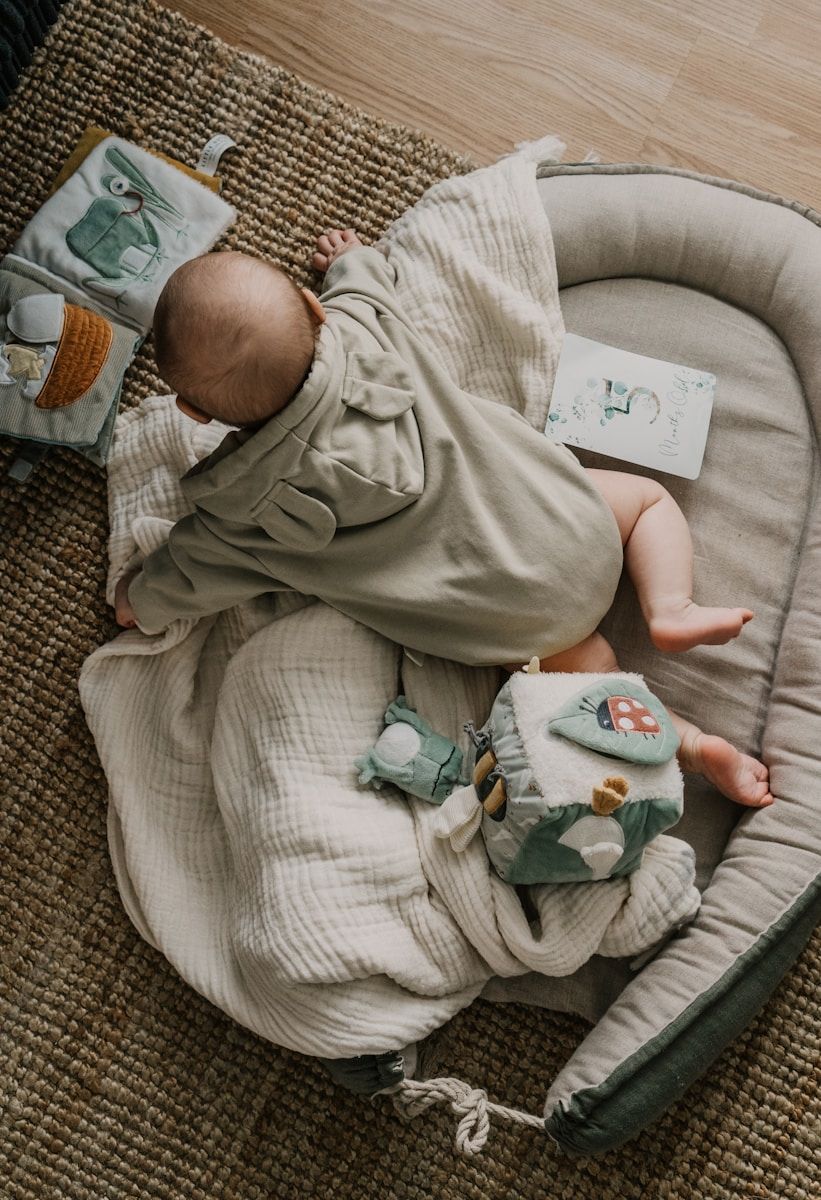 Bébé sur le ventre dans un coussin avec ses jouets