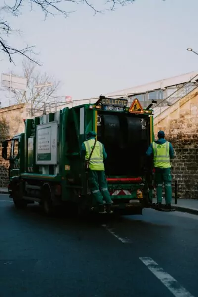 a couple of men standing on the back of a green truck